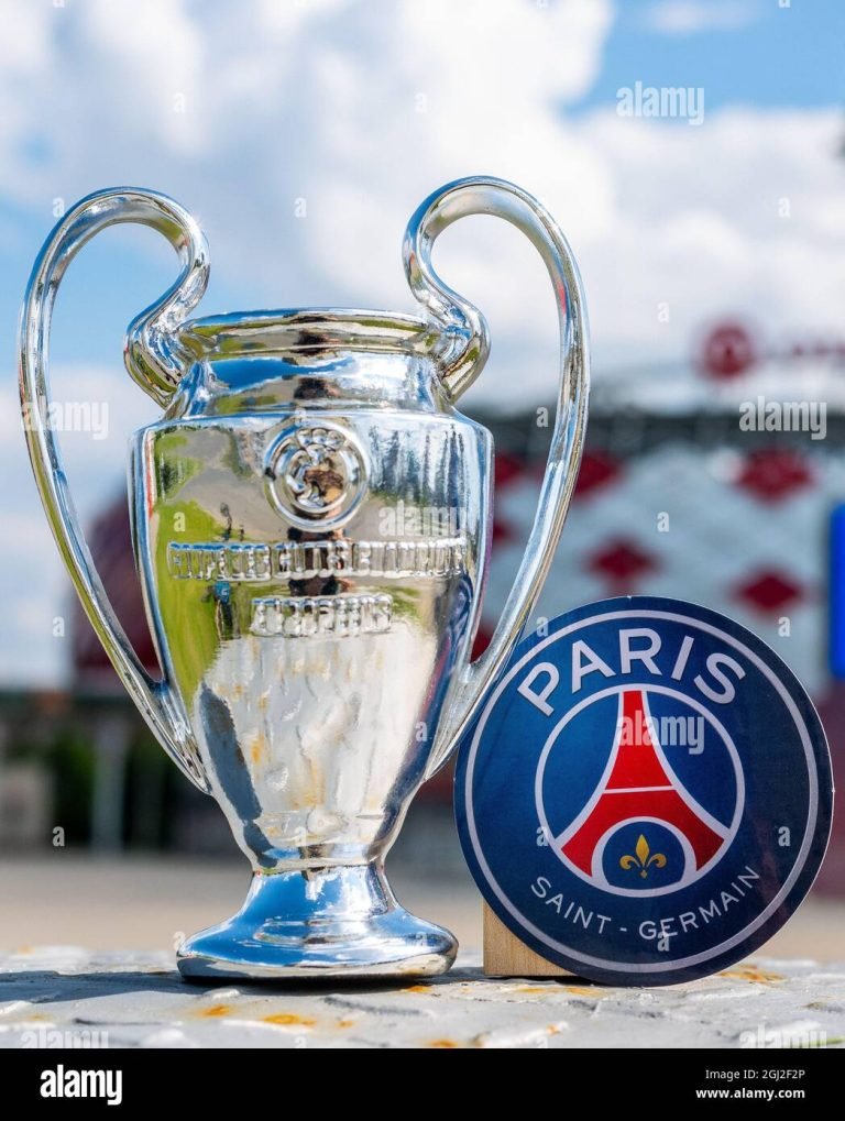 june-14-2021-paris-france-the-emblem-of-the-football-club-paris-saint-germain-fc-and-the-uefa-champions-league-cup-against-the-backdrop-of-a-mode-2GJ2F2P-3556280523